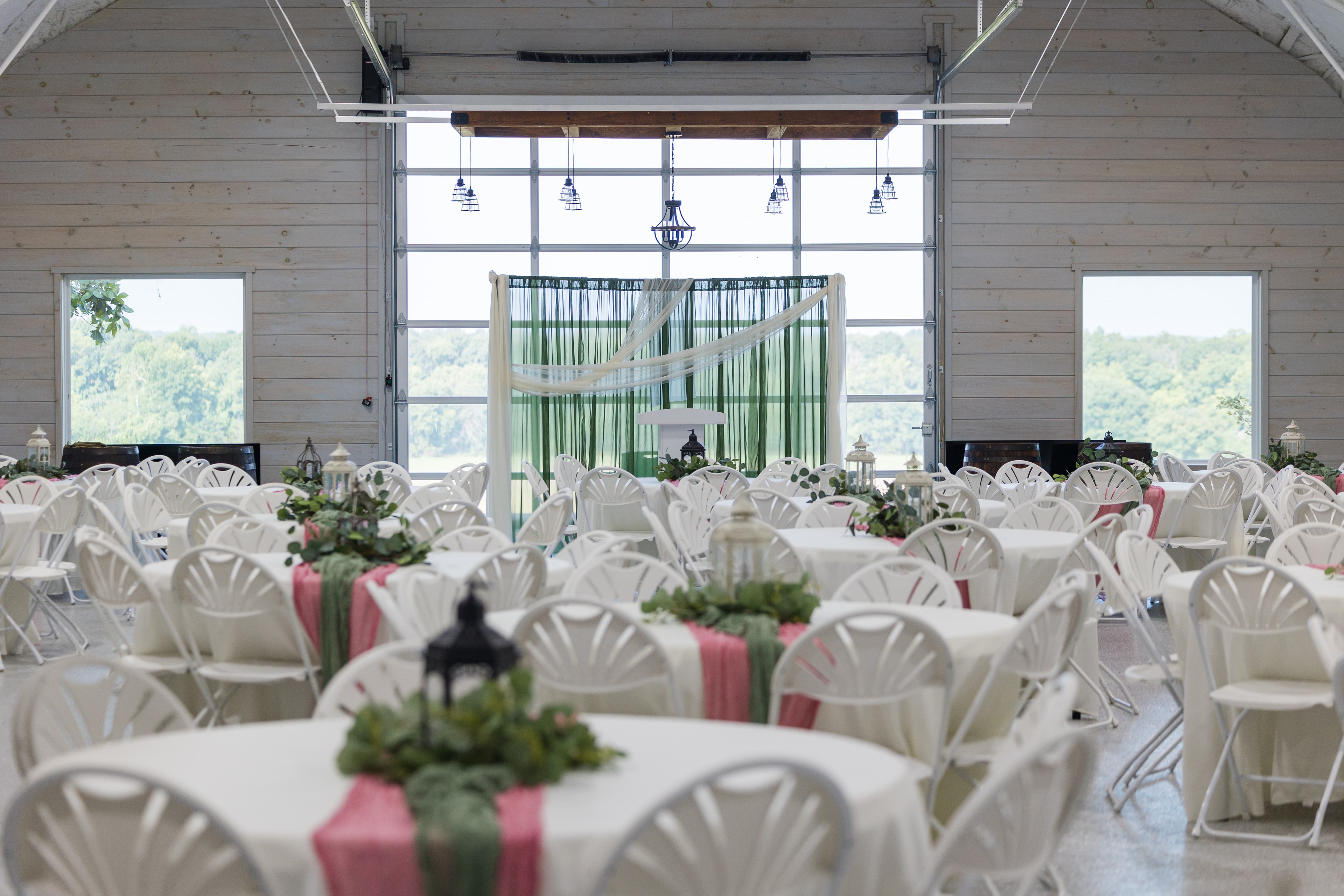 Wedding reception inside the venue with white chairs and floral centerpieces